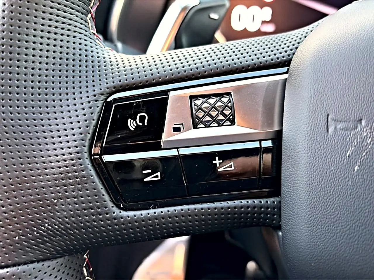 Gros plan sur les commandes gauche du volant en cuir perforé du DS7 noir, avec molette et boutons de réglage sonore.