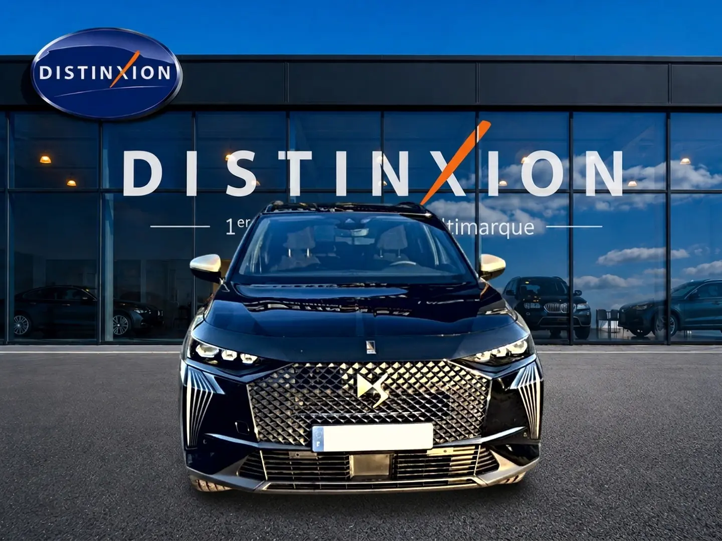 Vue frontale d'un DS7 noir 2026 avec calandre diamantée et phares LED distinctifs, devant une vitrine Distinxion.