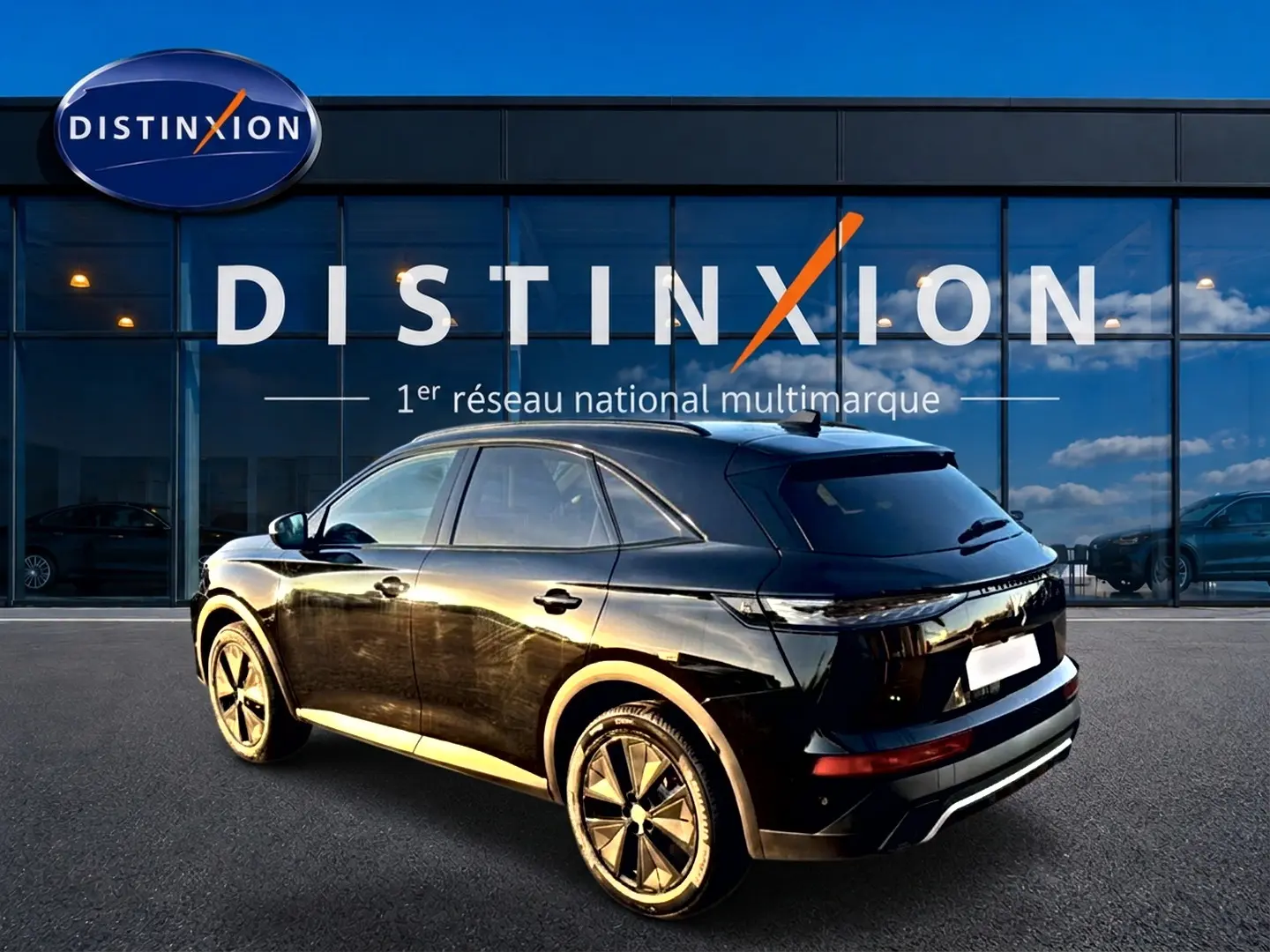 Vue 3/4 arrière droite du SUV DS7 noir brillant, avec jantes alu distinctives, devant une vitrine Distinxion.