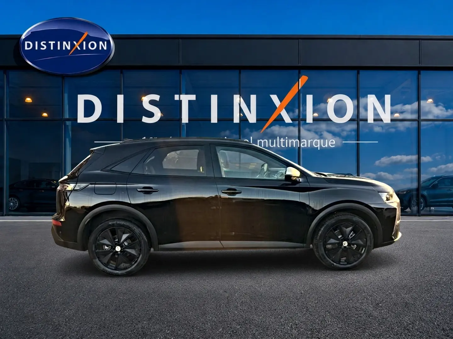 Vue de profil côté gauche d'un DS7 noir 2026 avec jantes noires, garé devant une vitrine Distinxion.