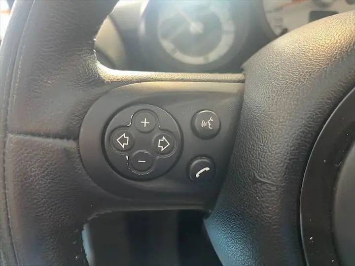 Gros plan sur les commandes noires du volant côté gauche d'une MINI Cooper Cabriolet noire de 2012.