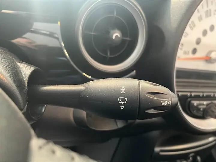 Gros plan sur la commande d'essuie-glace noire à gauche du volant dans l'habitacle d'une MINI Cooper Cabriolet noire 2012.