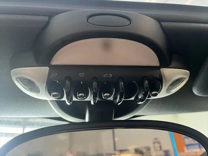 Vue en gros plan des commandes de toit ouvrant et éclairage au-dessus du rétroviseur intérieur d'une MINI Cooper Cabriolet noire de 2012.