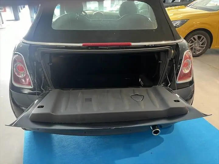 Vue arrière d'une MINI Cooper cabriolet noire de 2012 avec coffre ouvert, dévoilant l'espace de rangement intérieur.