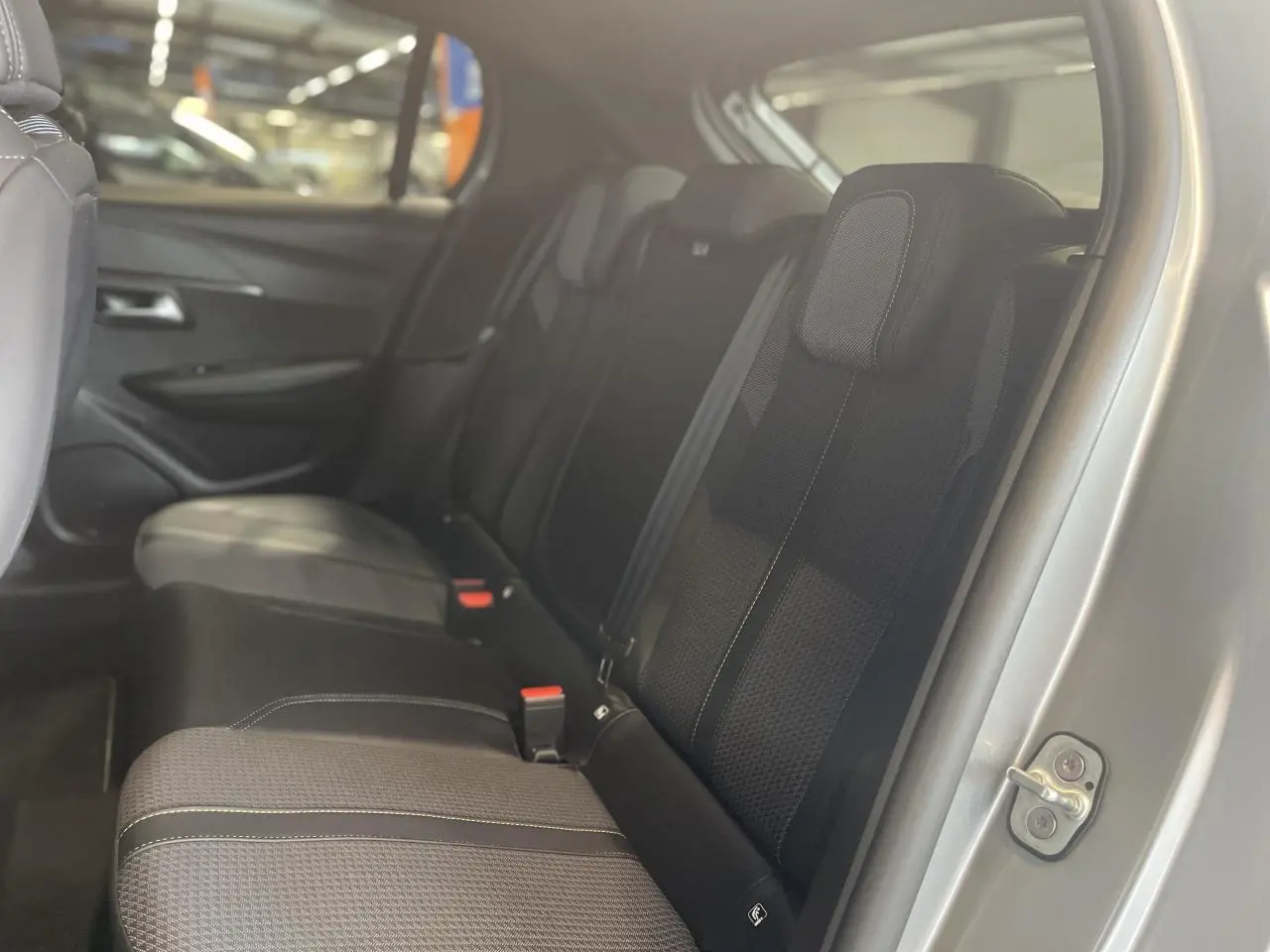 Vue intérieure côté droit sur la banquette arrière noire de la Peugeot 208 gris clair métallisé.