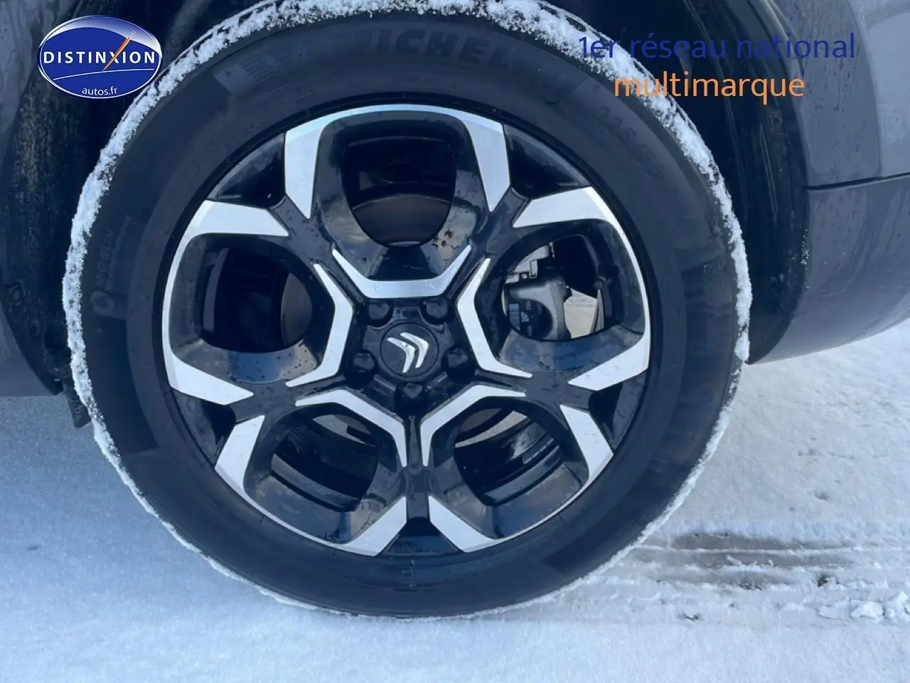 Gros plan sur la jante alu noire et argentée du côté gauche d’un Citroën C5 Aircross gris platinium sur neige.