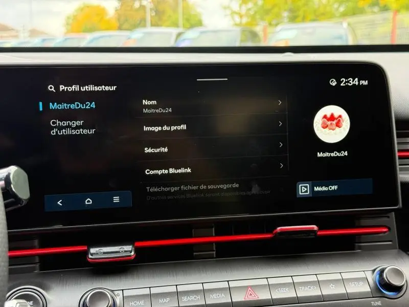 Écran tactile central du Hyundai Kona 2025 affichant le menu profil utilisateur, avec bandeau décoratif rouge en dessous.