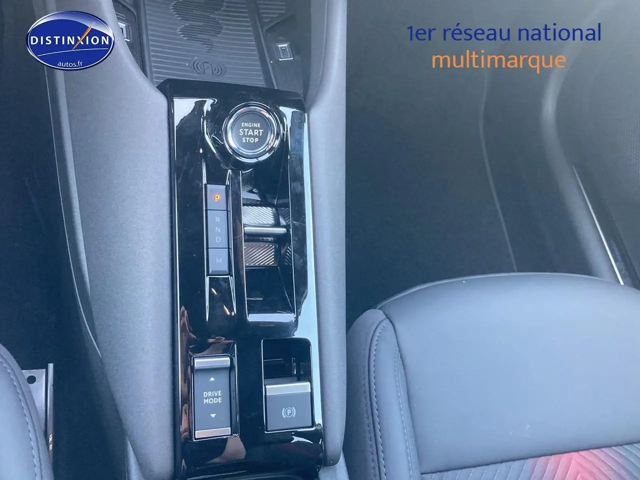 Gros plan sur la console centrale noire brillante de l'Alfa Romeo Junior 1.2 hybride, avec bouton start/stop et levier de vitesses.