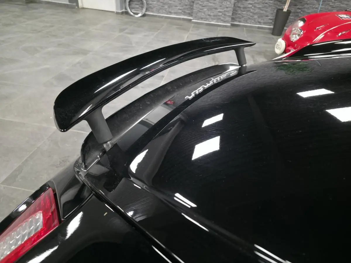 Vue rapprochée de l’aileron arrière noir sur Porsche Cayman 2.7i 2008 avec carrosserie noire brillante.