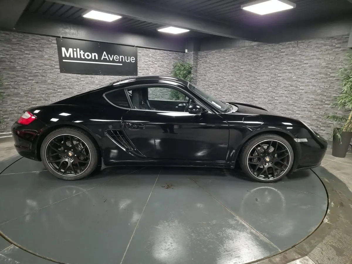 Profil côté gauche de la Porsche Cayman 2.7i noire de 2008 avec jantes SportDesign noires de 19 pouces.