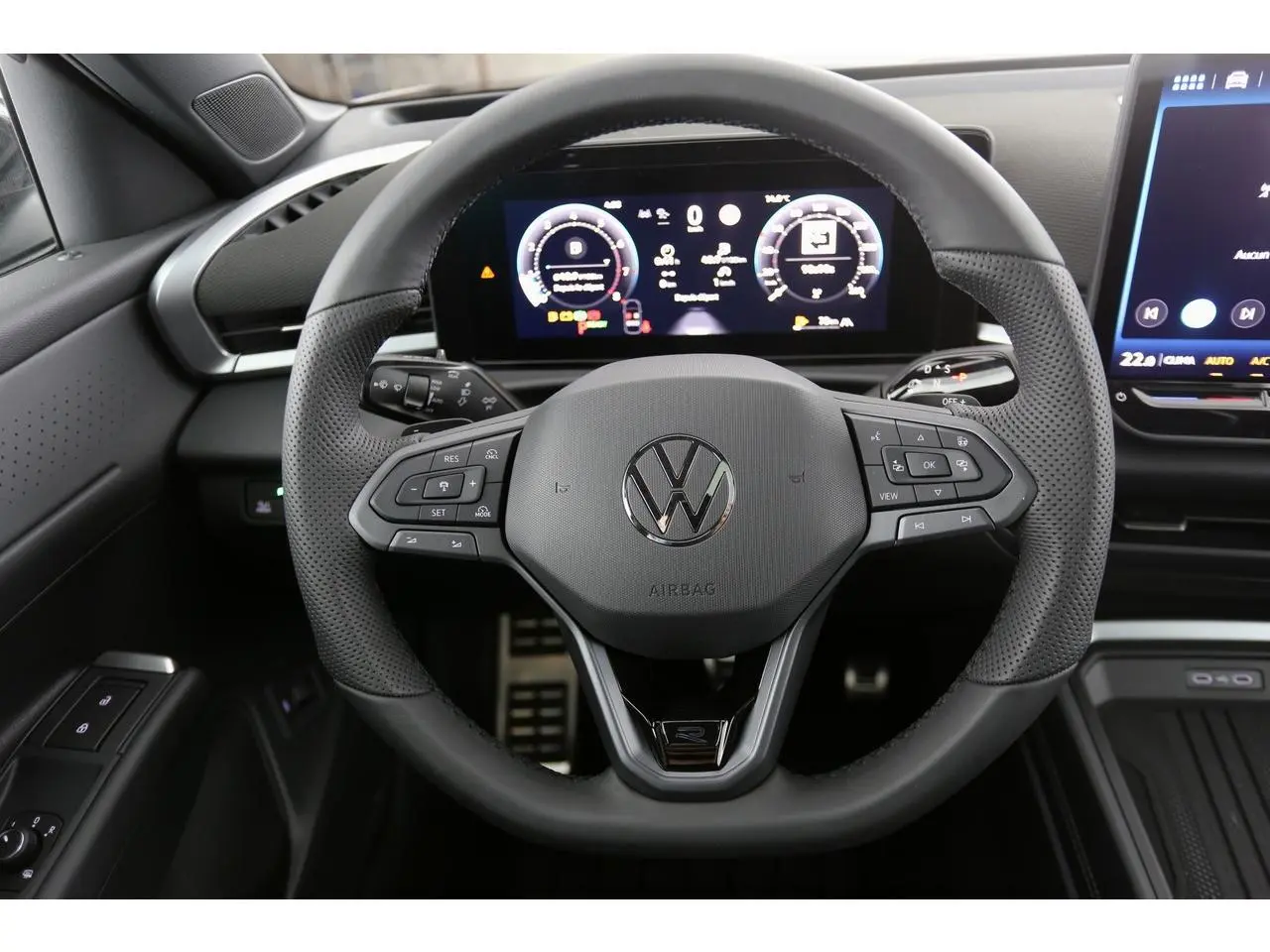 Vue rapprochée du volant sport en cuir noir du Volkswagen T-Roc 2026 avec tableau de bord numérique et commandes intégrées.
