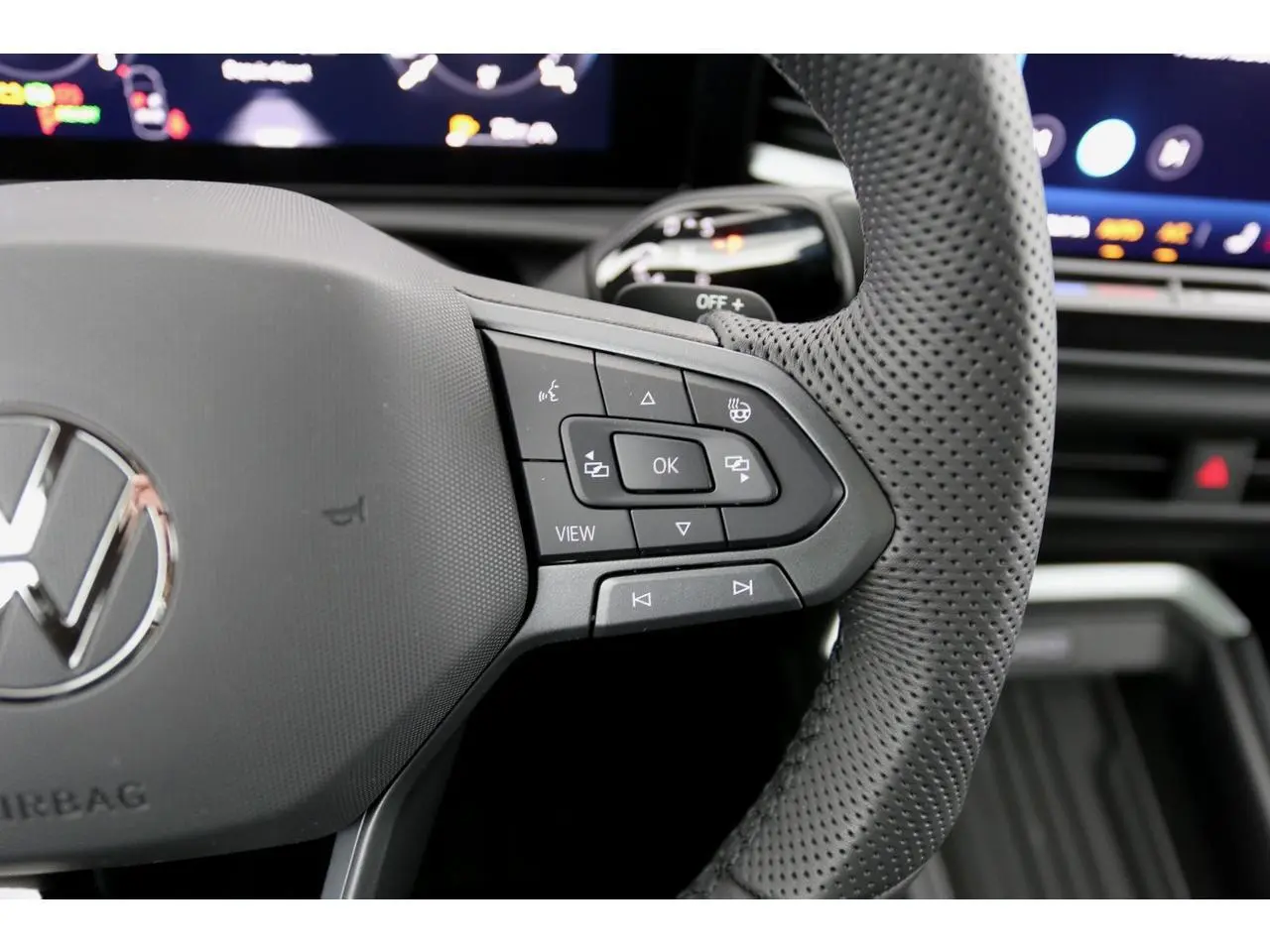 Gros plan sur le volant perforé gris du Volkswagen T-Roc 2026, avec commandes multifonctions visibles à droite.