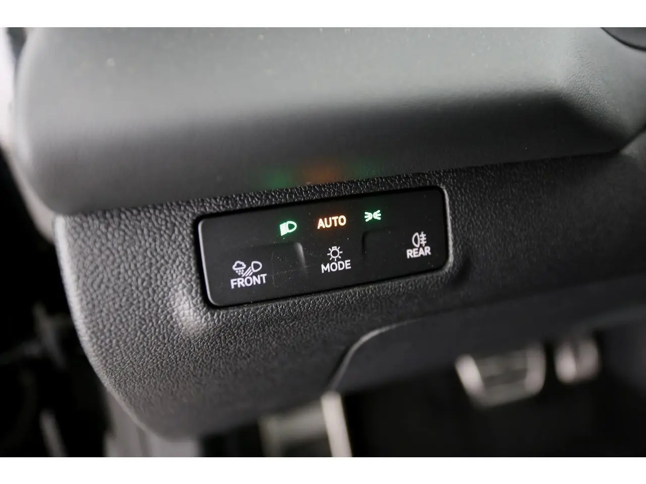Gros plan sur le bouton de réglage automatique des feux dans un Volkswagen T-Roc gris Loup 2026.