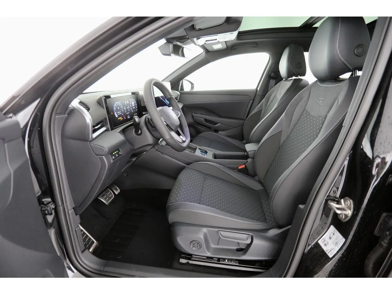 Vue intérieure côté conducteur du Volkswagen T-Roc 2026 avec sièges sport tissu R-Line noirs et tableau de bord digital.