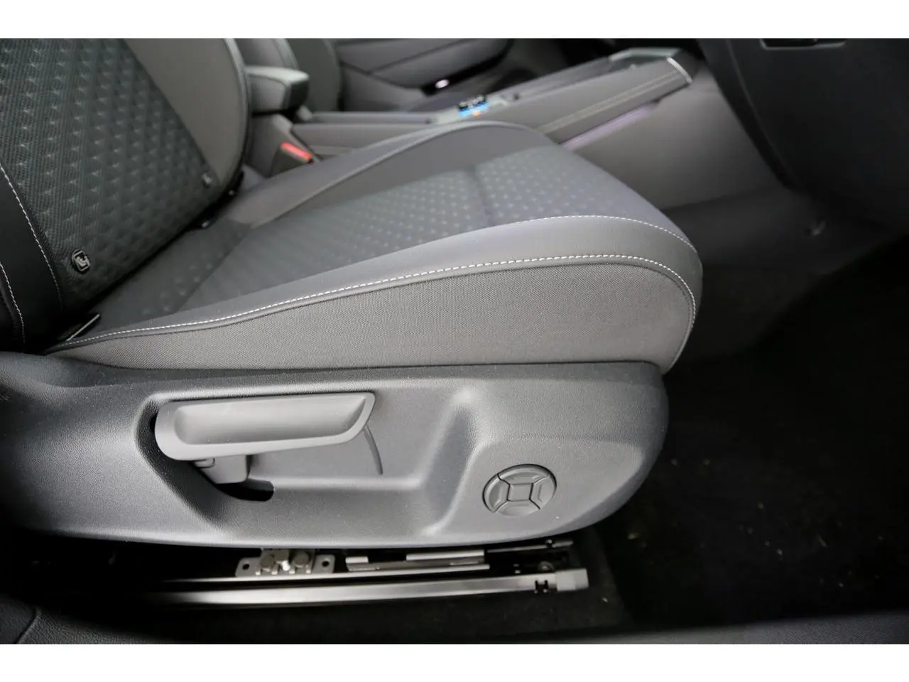 Détail du siège avant gauche en tissu gris avec réglages manuels dans l'habitacle du Volkswagen T-Roc 2026.