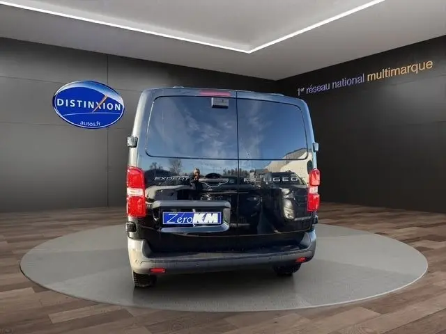 Vue arrière d’un Peugeot Expert Fourgon noir 2025, avec portes battantes fermées et logo visible sur fond showroom.