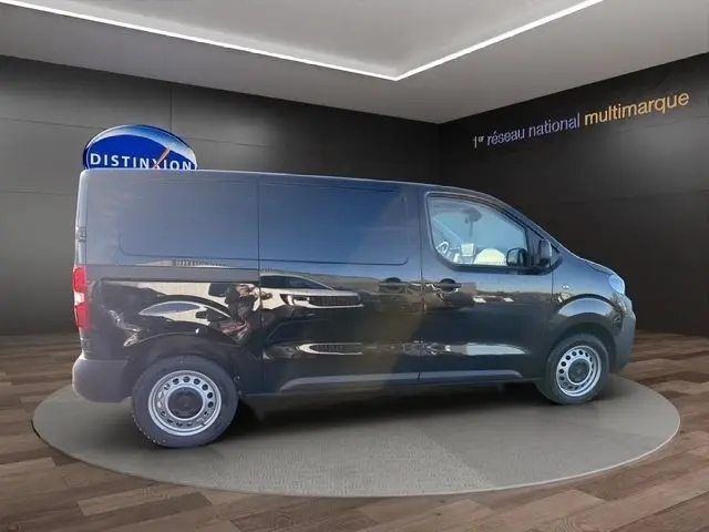 Vue de profil côté droit d'un Peugeot Expert Fourgon noir stationné en intérieur sur un podium circulaire.