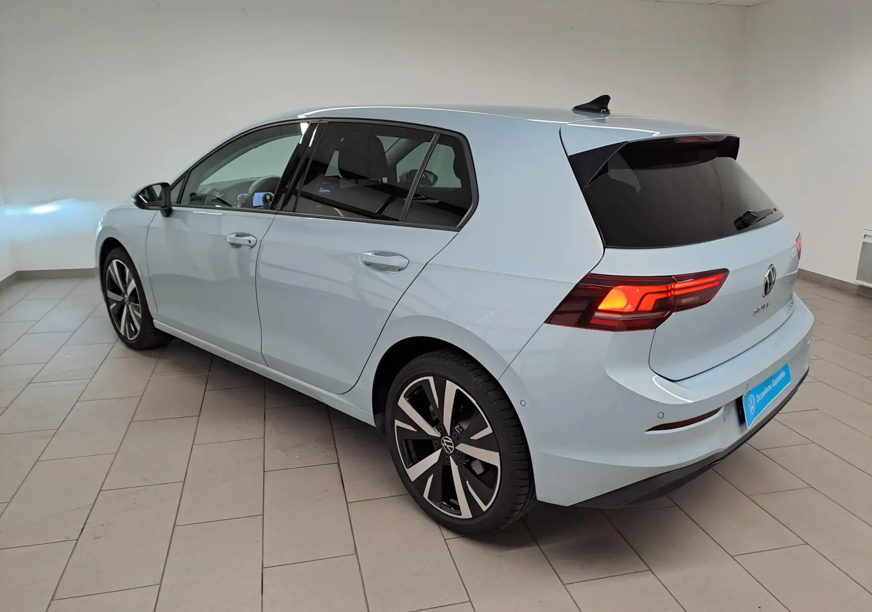 Vue 3/4 arrière droite d'une Volkswagen Golf 1.5 eTSI 2025 en Bleu Glacier avec jantes alliage 18'' Catania.
