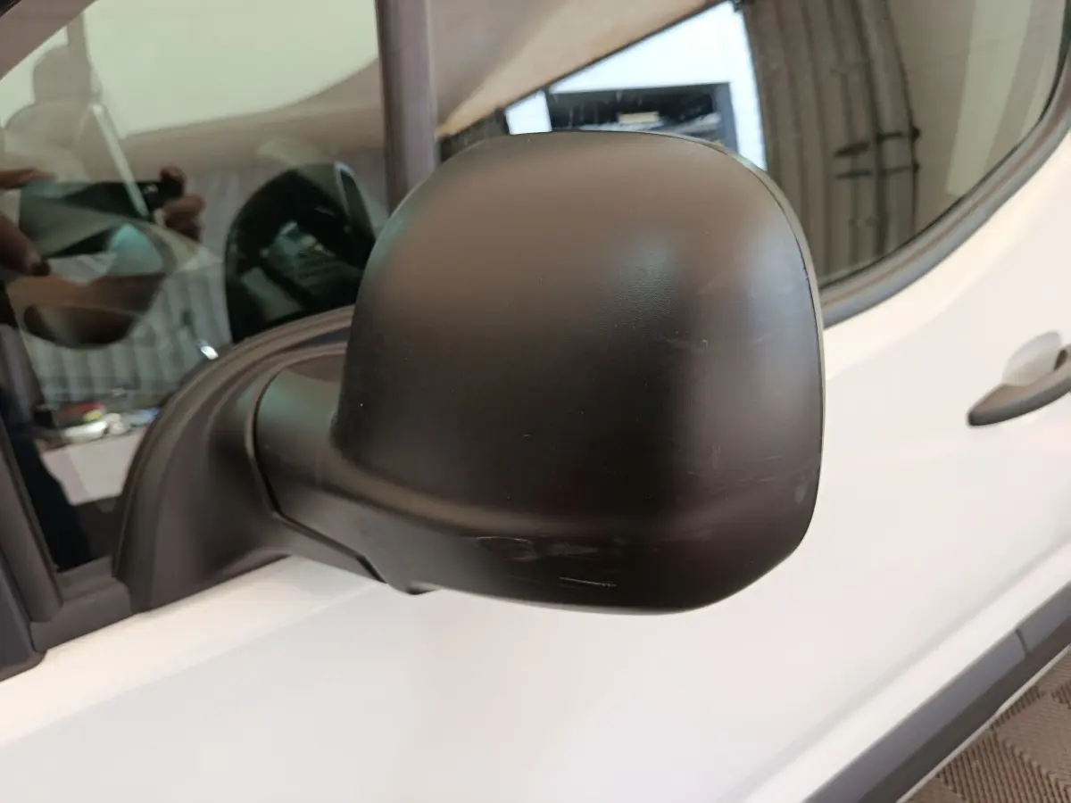 Rétroviseur extérieur noir côté conducteur du Peugeot Partner blanc, vue rapprochée en léger angle avant.