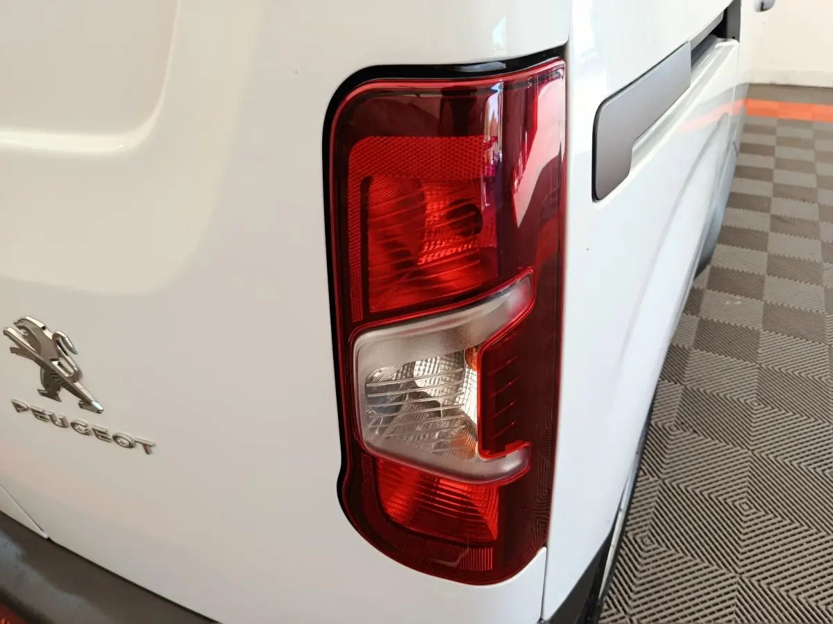 Gros plan sur le feu arrière droit rouge et blanc d’un Peugeot Partner blanc, vue arrière côté droit.