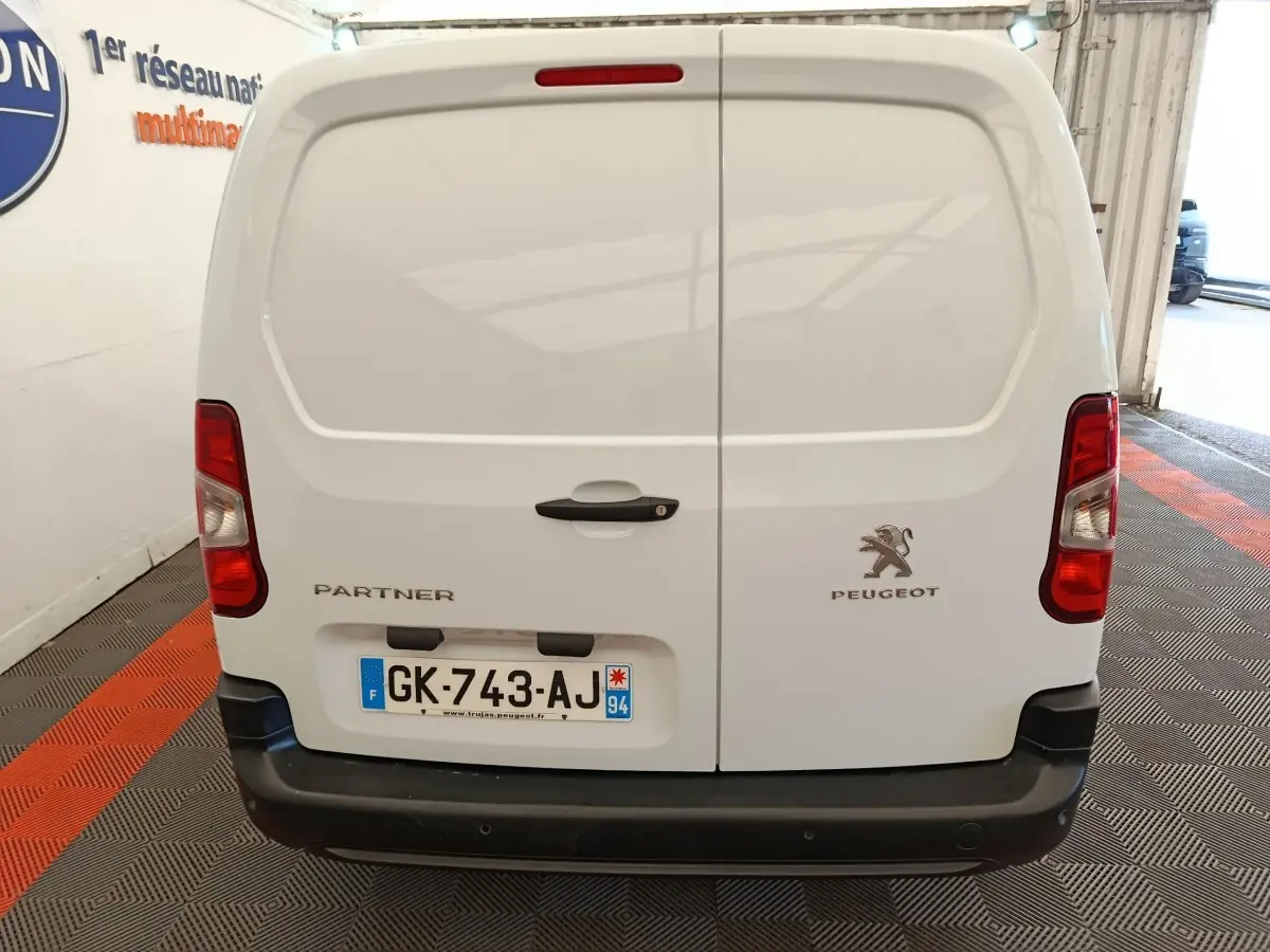 Vue arrière d’un Peugeot Partner blanc 2022 avec portes battantes et feux rouges verticaux, immatriculé en France.