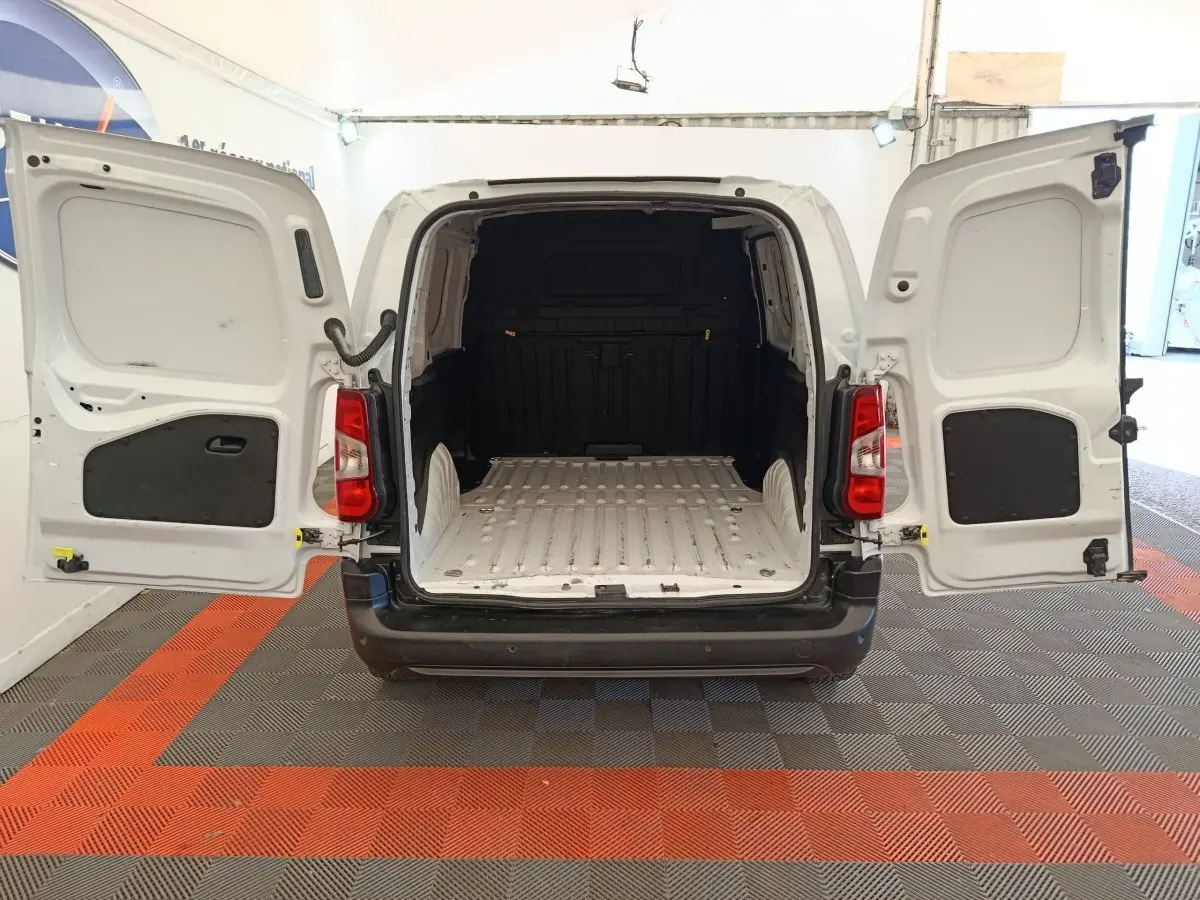 Vue arrière d’un Peugeot Partner blanc 2022 avec portes battantes ouvertes montrant l’espace de chargement vide.