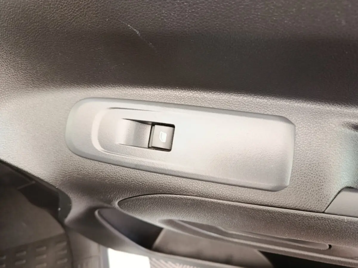 Gros plan sur l'interrupteur de lève-vitre côté conducteur dans l'habitacle du Peugeot Partner blanc.