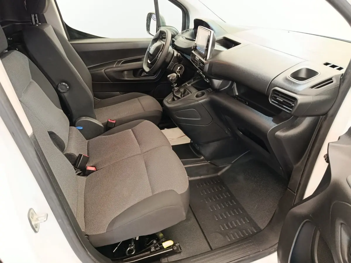 Vue intérieure côté conducteur du Peugeot Partner 2022 avec sièges gris et tableau de bord noir moderne.