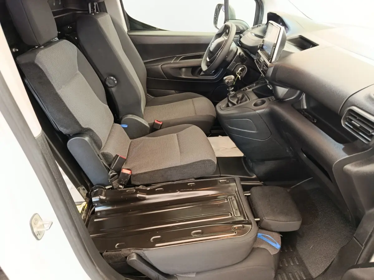 Vue intérieure côté conducteur du Peugeot Partner blanc 2022, montrant les sièges avant et la console centrale avec boîte manuelle.