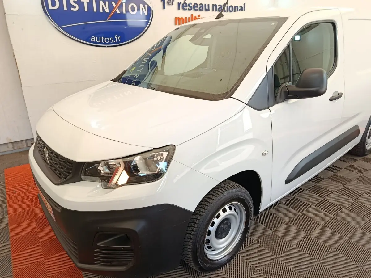 Peugeot Partner blanc vu en 3/4 avant droit, avec pare-chocs noir mat et jantes acier simples.