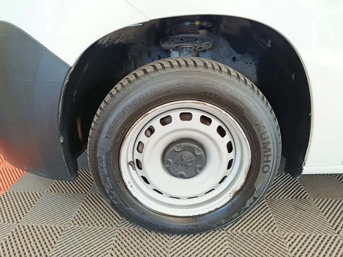 Gros plan sur la roue avant gauche blanche d’un Peugeot Partner blanc, avec jante acier et pneu Kumho visible.