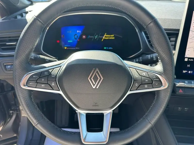 Vue rapprochée du volant noir et du tableau de bord numérique du Renault Symbioz rouge de 2025.