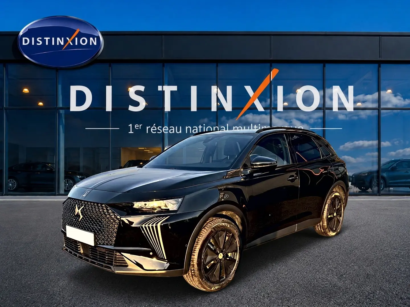 DS7 noir vue 3/4 avant droit, avec calandre distinctive DS et jantes alliage noires devant un showroom Distinxion.