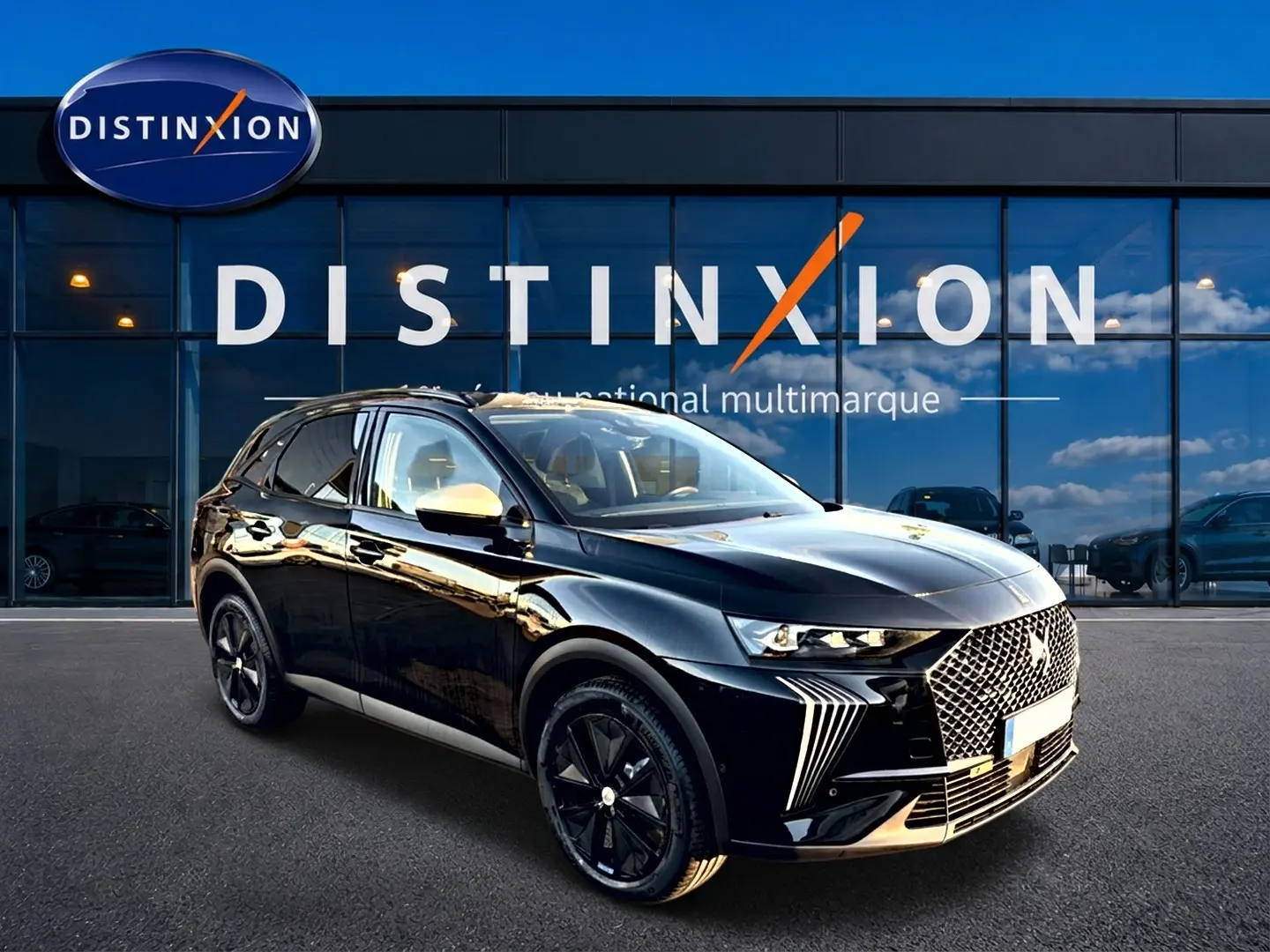 DS7 noir 2026 en 3/4 avant droit, avec calandre distinctive et jantes noires brillantes devant un showroom Distinxion.