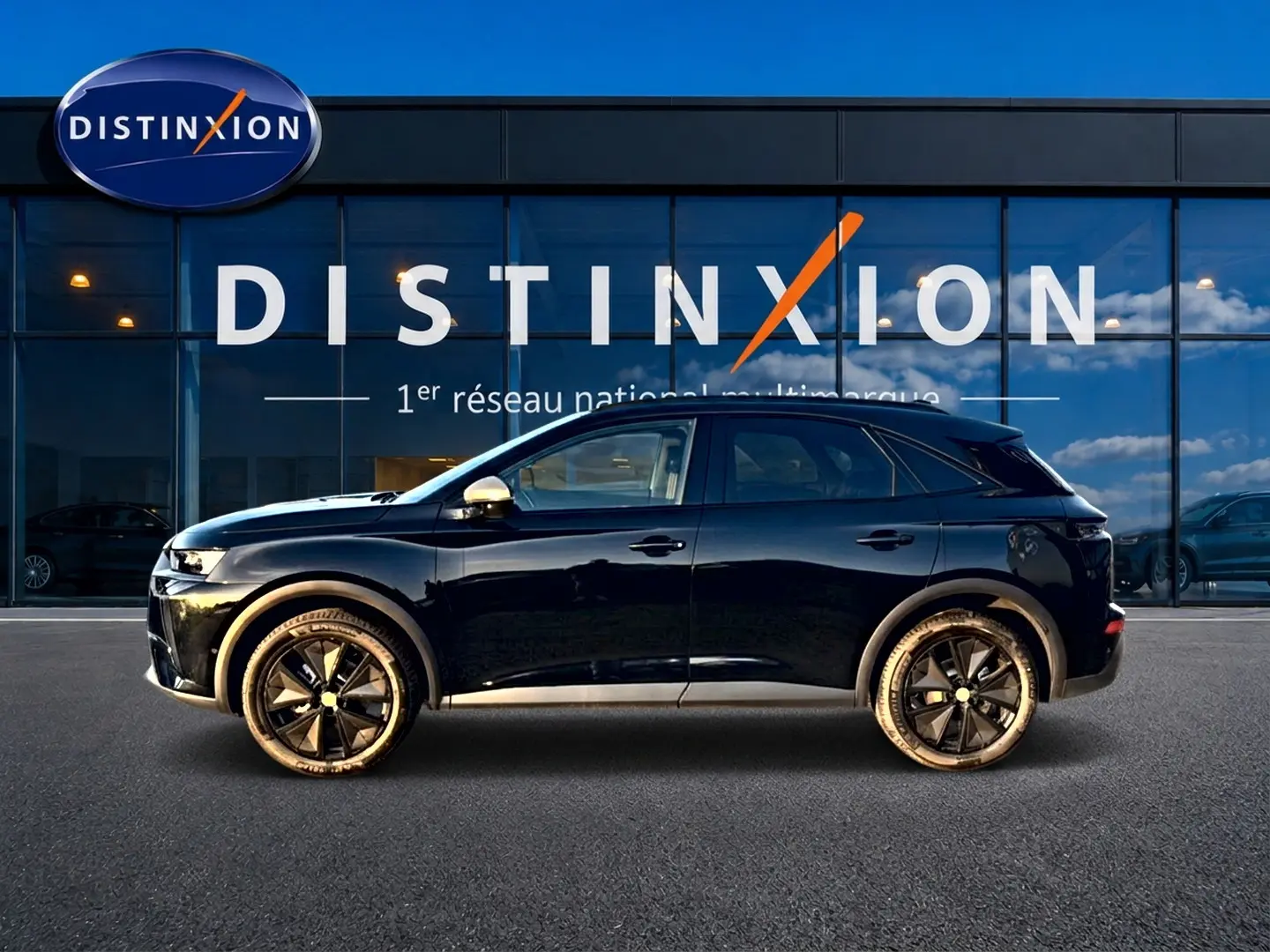 Vue de profil côté gauche d'un DS7 noir 2026 garé devant une vitrine avec logo Distinxion.