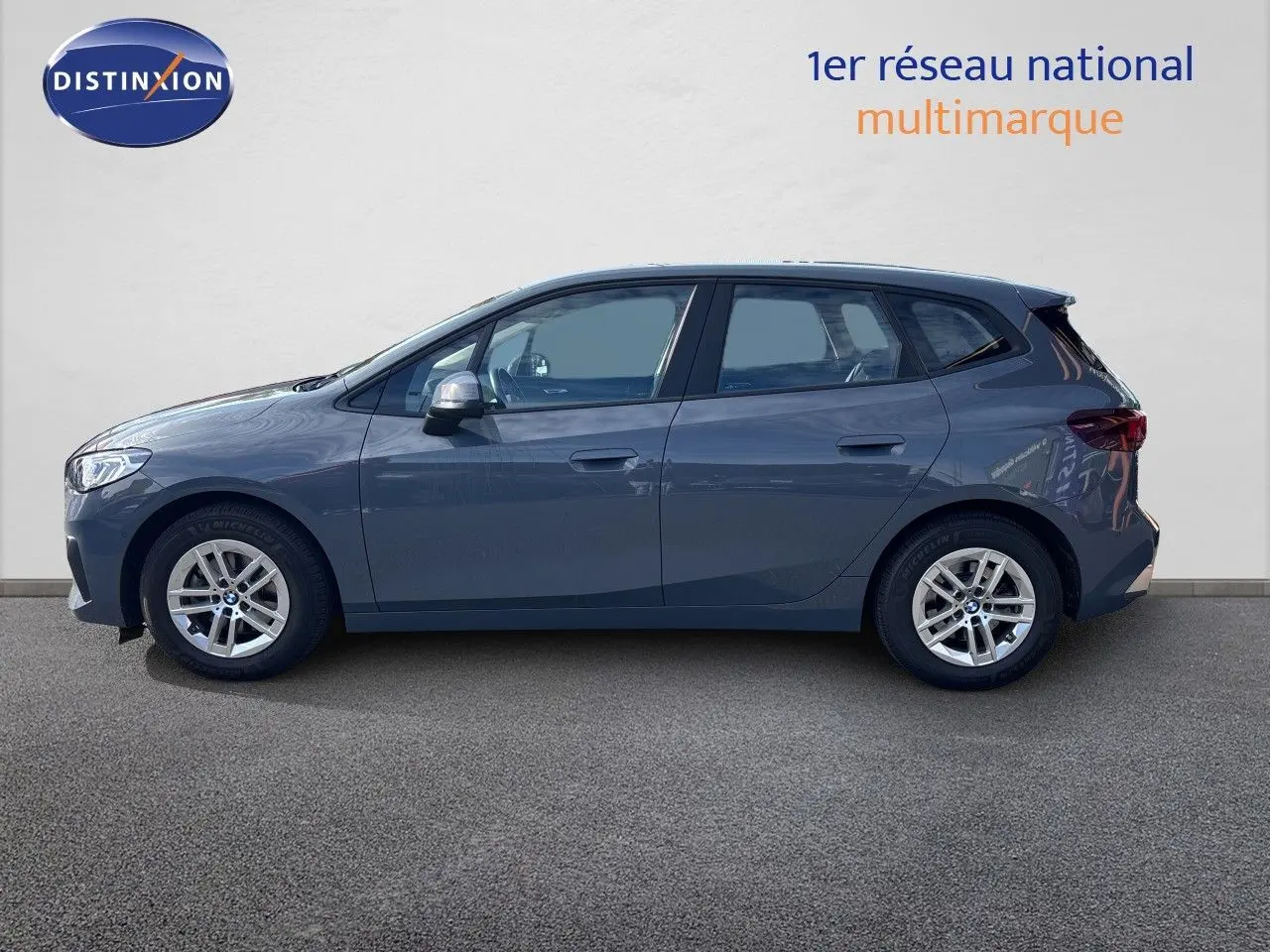 BMW Série 2 Active Tourer 218d gris cuivré vue de profil côté gauche sur fond neutre, jantes alliage visibles.