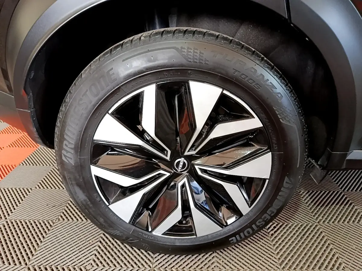 Gros plan sur la roue avant droite noire avec jante alliage bicolore du Nissan Juke 2023 DIG-T 114 BVM6 Acenta.