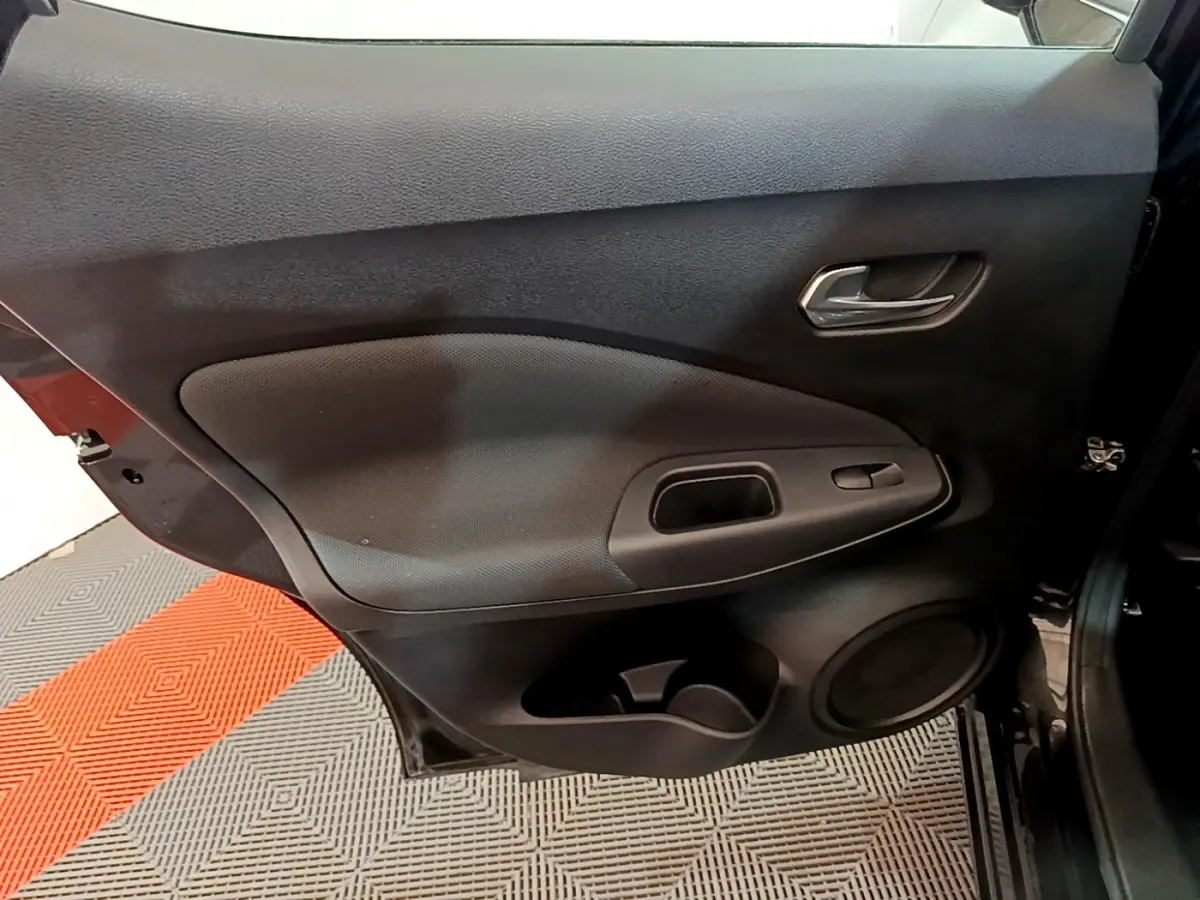 Vue intérieure côté gauche de la porte arrière noire du Nissan Juke 2023 avec poignée et commande de fenêtre intégrée.