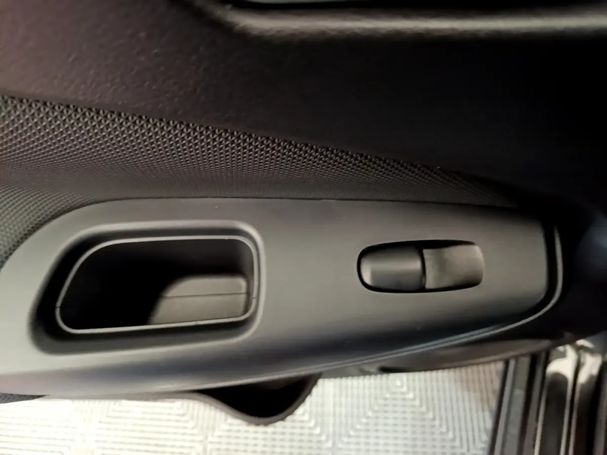 Gros plan sur la poignée intérieure de porte côté conducteur du Nissan Juke noir 2023, avec commande de verrouillage.