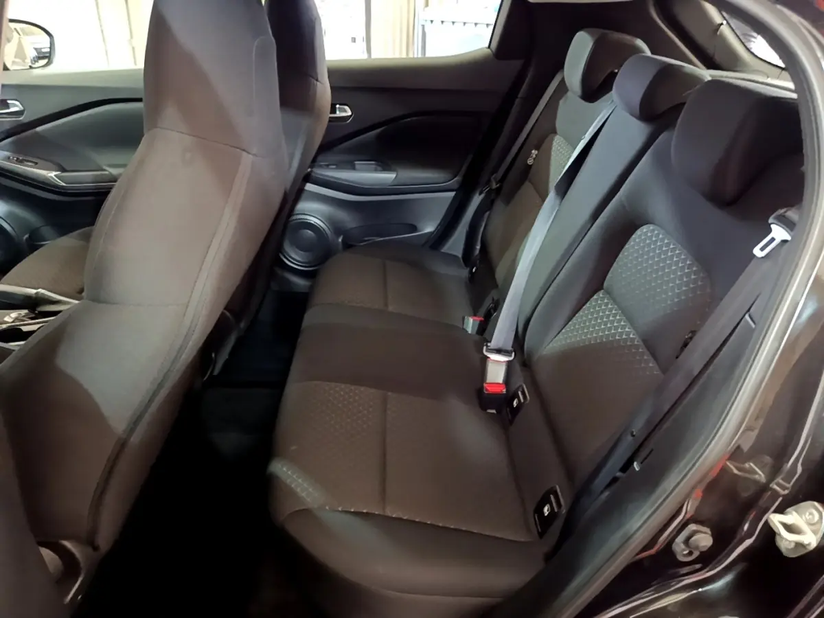 Vue intérieure côté droit montrant la banquette arrière noire du Nissan Juke 2023 avec ceintures et appuie-têtes intégrés.