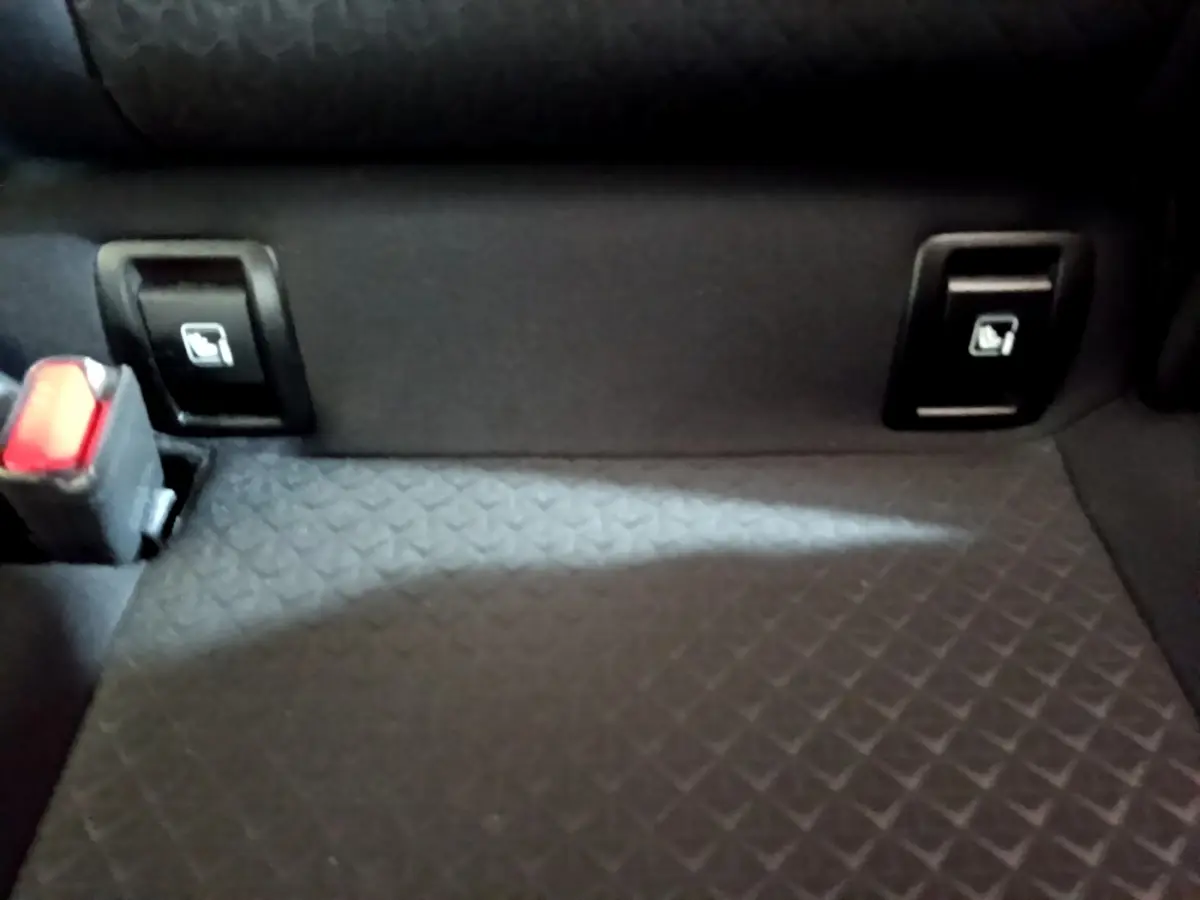 Détail de la banquette arrière noire du Nissan Juke 2023 avec commandes rabattables et ceinture de sécurité.
