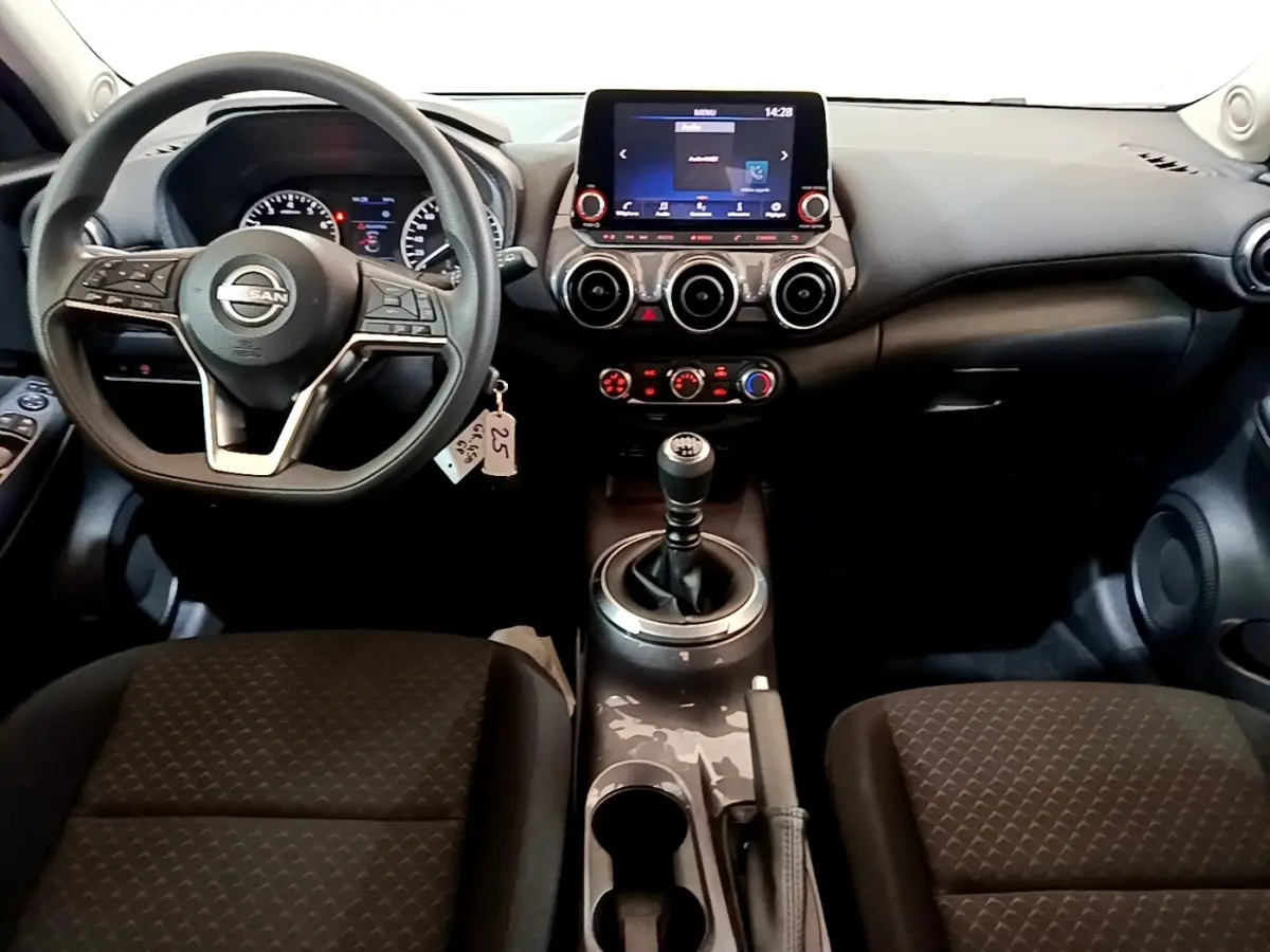 Vue intérieure frontale du tableau de bord noir du Nissan Juke 2023 avec volant multifonctions et écran tactile central.