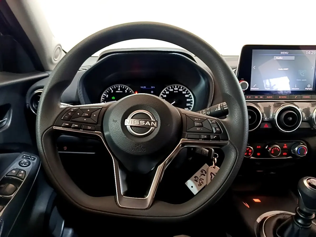 Vue intérieure centrée sur le volant multifonctions noir d’un Nissan Juke 2023 avec tableau de bord et écran tactile.