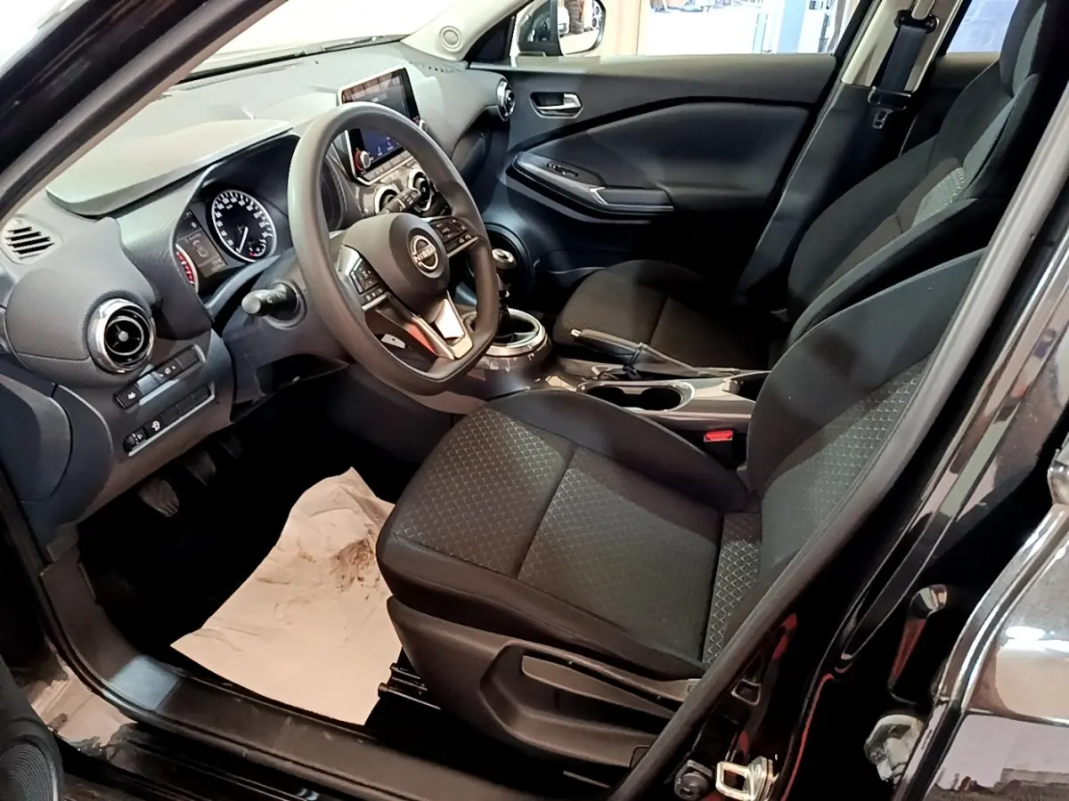 Intérieur noir du Nissan Juke 2023 vu côté conducteur, avec volant multifonctions et tableau de bord digital.