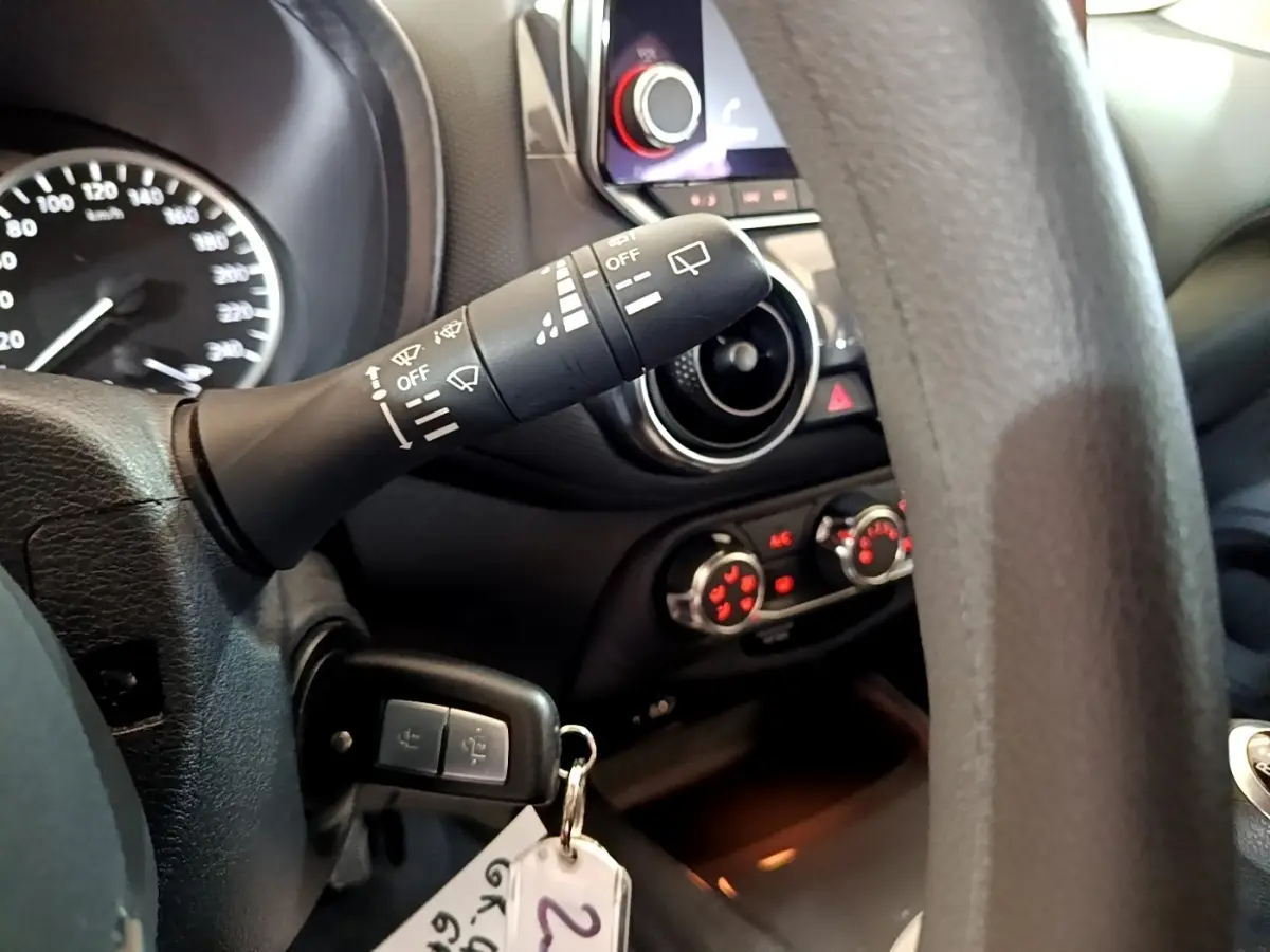 Gros plan intérieur côté gauche du volant noir du Nissan Juke 2023, avec commandes d'essuie-glace et tableau de bord.