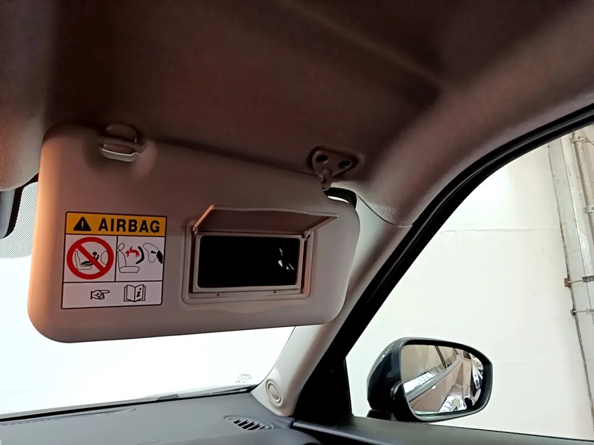 Détail du pare-soleil côté conducteur avec miroir intégré et avertissement airbag dans un Nissan Juke noir 2023.