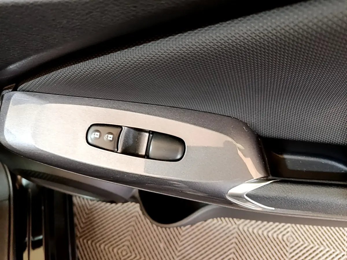 Gros plan sur la commande de verrouillage des portes côté conducteur du Nissan Juke noir 2023.