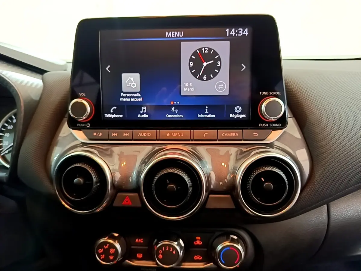 Vue rapprochée du tableau de bord noir du Nissan Juke 2023 avec écran tactile et commandes circulaires d’aération.