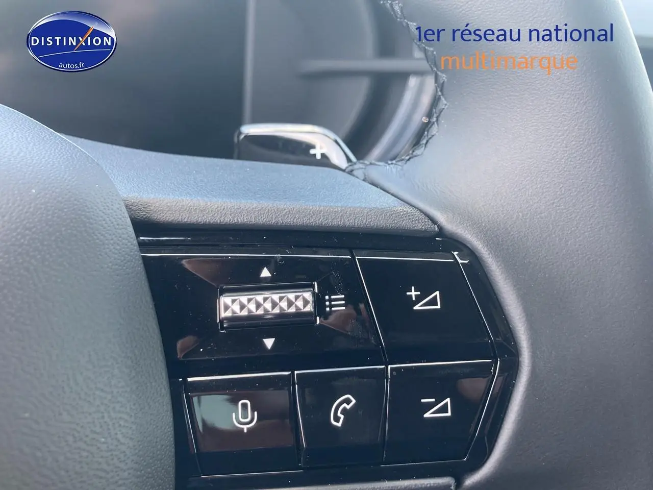 Gros plan sur les commandes au volant côté gauche de l'Alfa Romeo Junior gris, avec boutons de volume et téléphone.