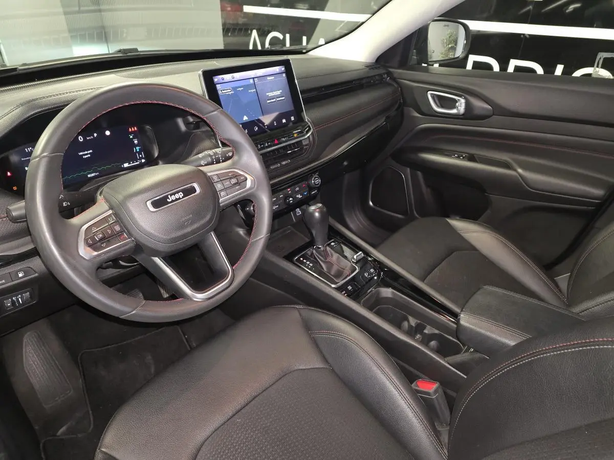 Vue intérieure côté conducteur du Jeep Compass noir 2022, avec tableau de bord numérique et console centrale moderne.